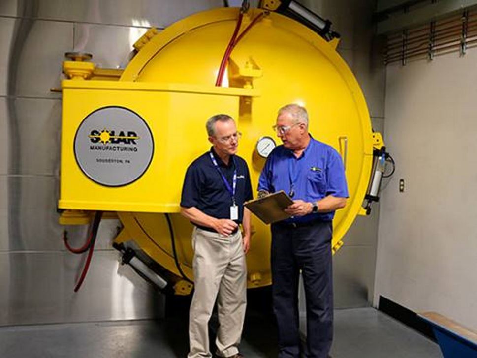 Air Products' technical expert in discussion with a customer in front of a Solar vacuum furnace
